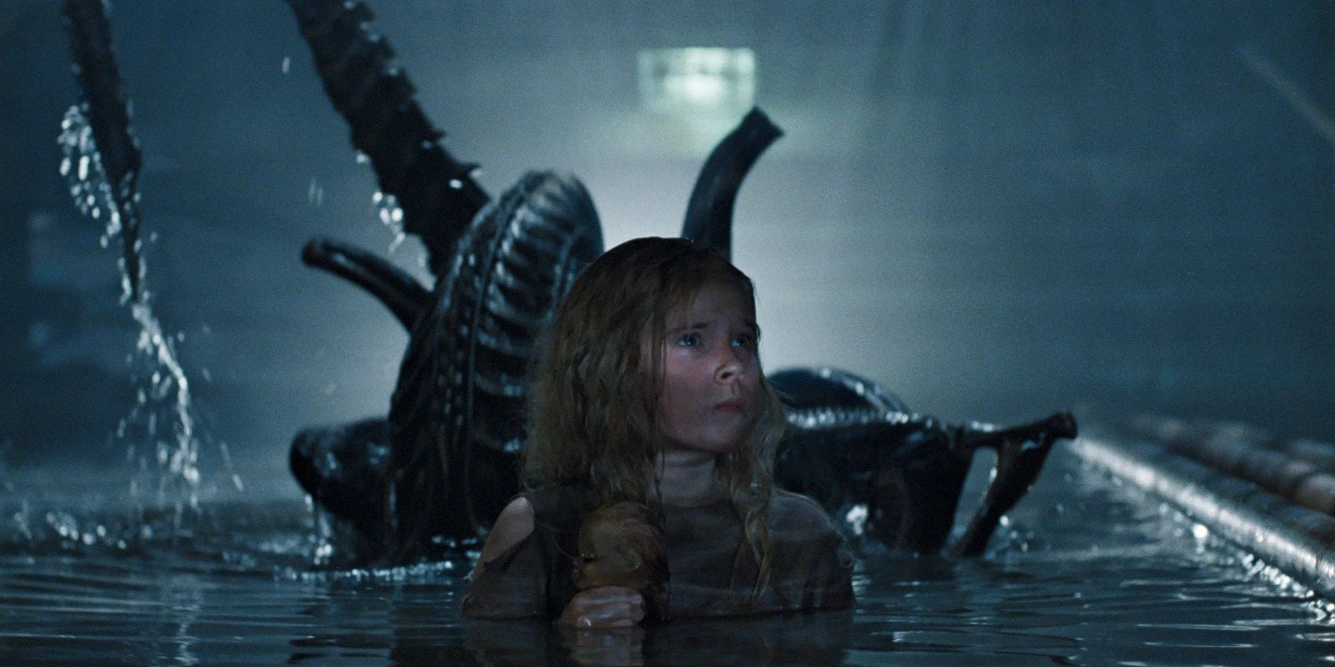 An alien rises up behind Newt in a sewer in Aliens.