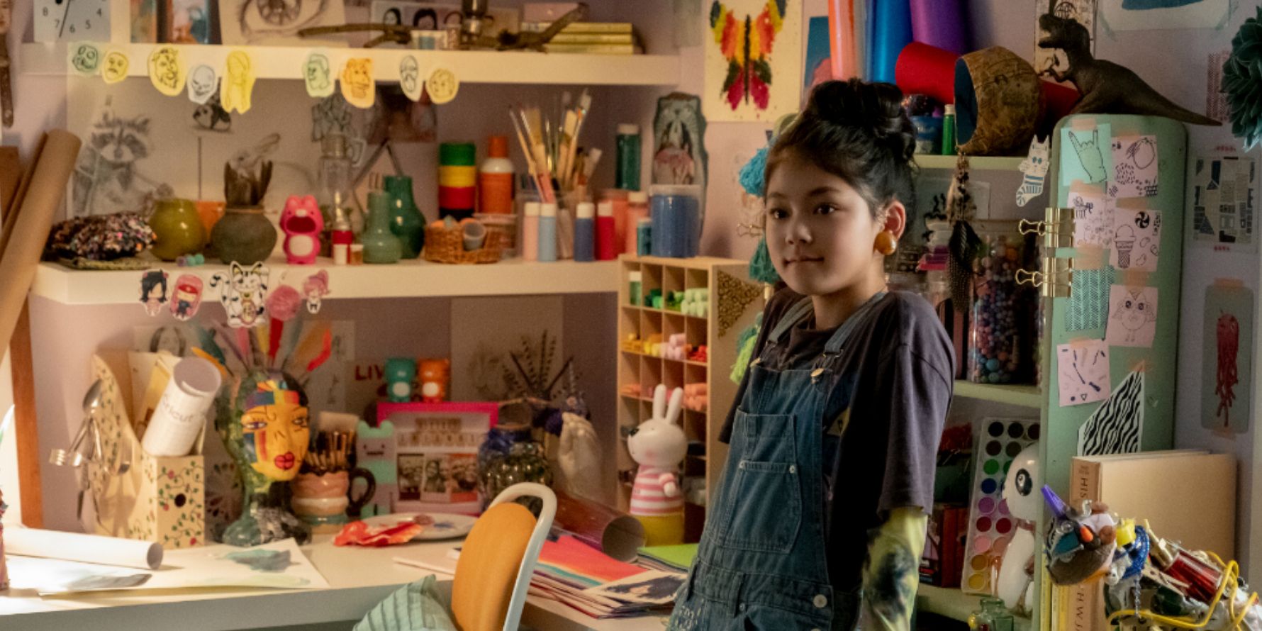 Claudia leans on her cluttered art desk in The Baby-Sitters Club
