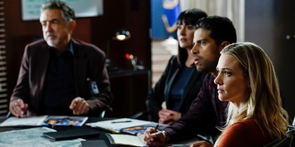 Criminal minds characters sat at a table listening in a meeting