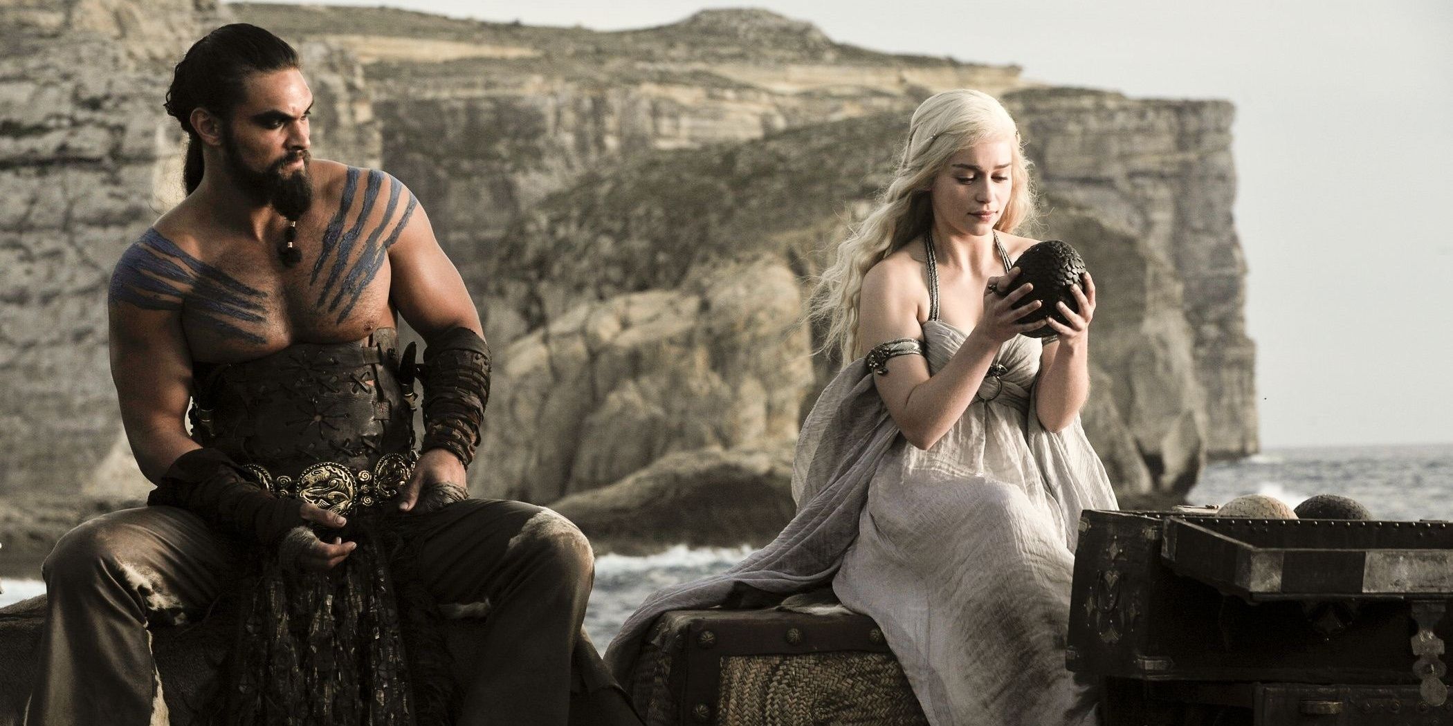 Khal Drogo with Daenerys Targaryen sitting together as she looks at a dragon egg in Game of Thrones 