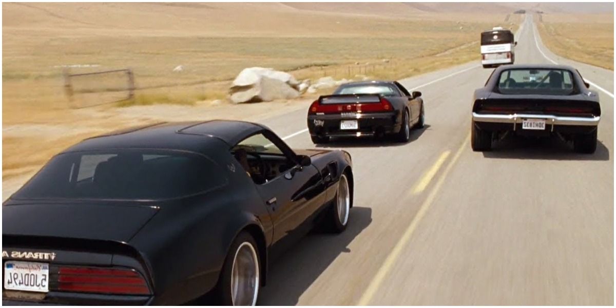 Three black cars approach the prison bus on an empty road in Fast Five