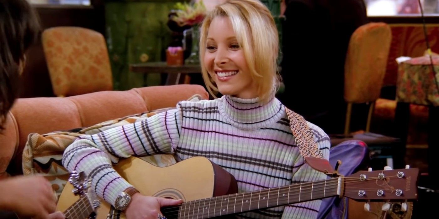 Phoebe holding a guitar and smiling in Central Perk in Friends