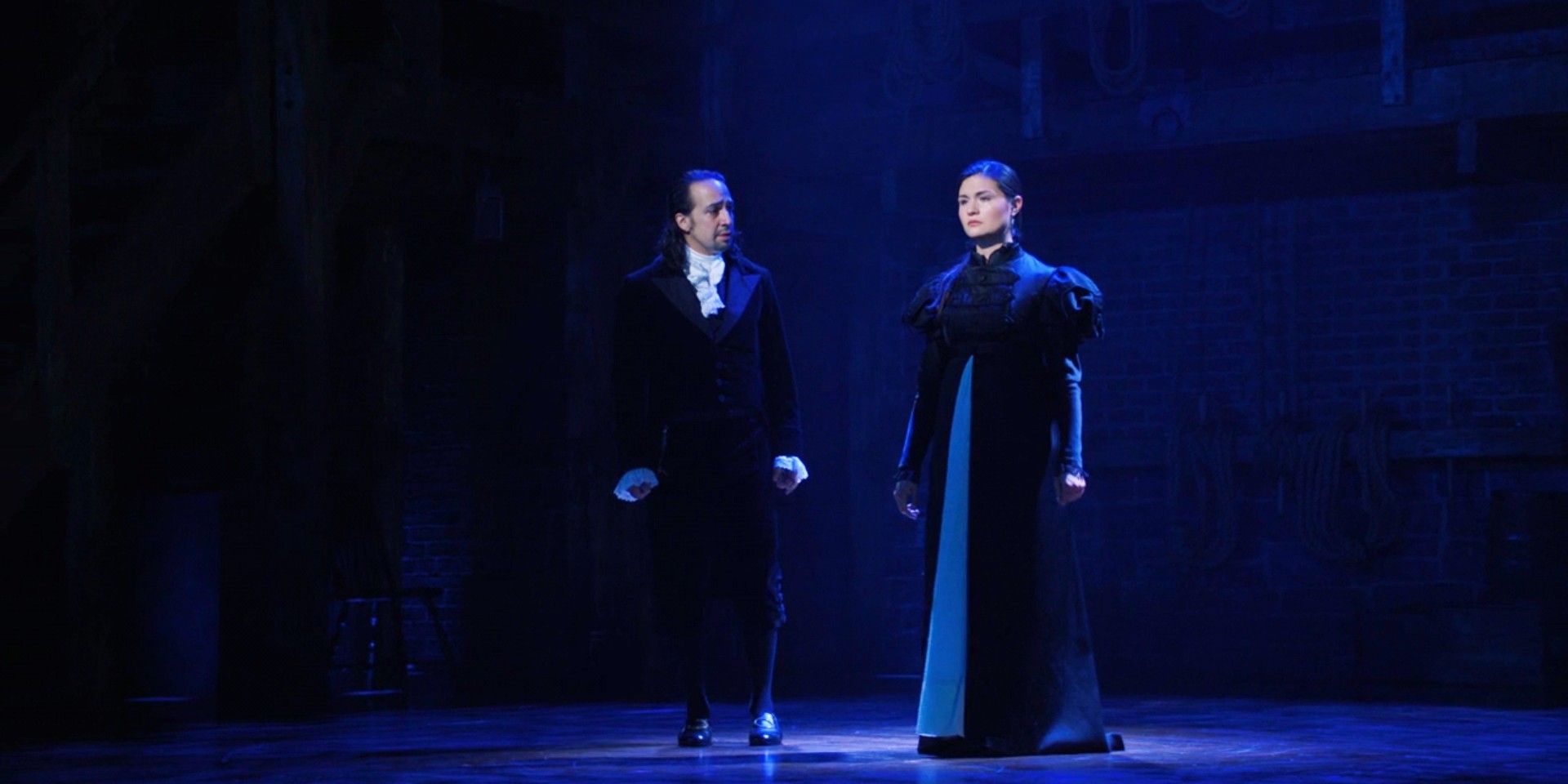 Alexander and Eliza in dark clothes on a dark stage in Hamilton