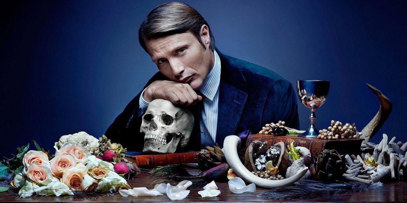Hannibal sits at a table of bones and flowers in a promotional image for the show