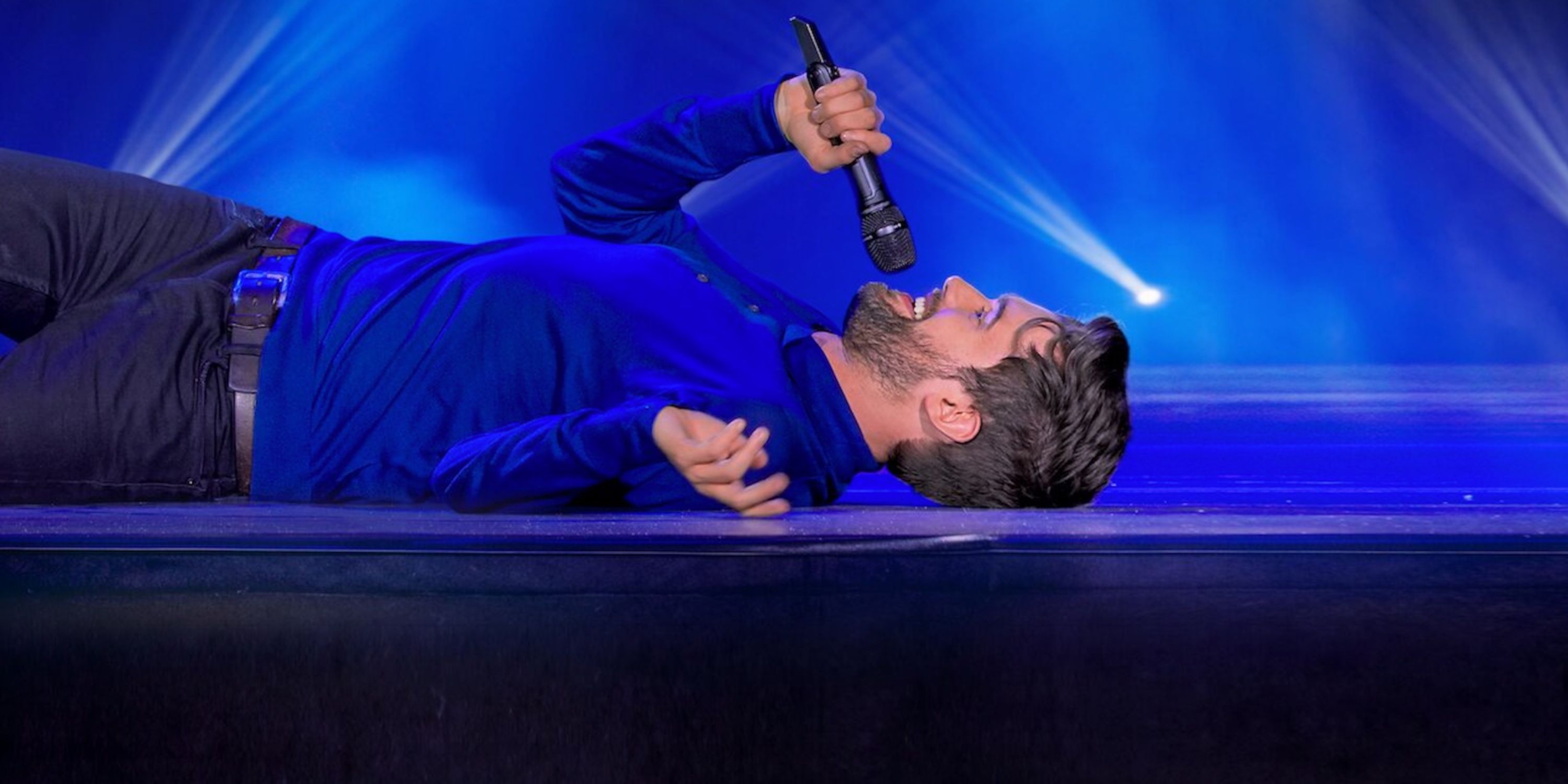 Jack Whitehall in I'm Only Joking on Netflix laying down on the stage.
