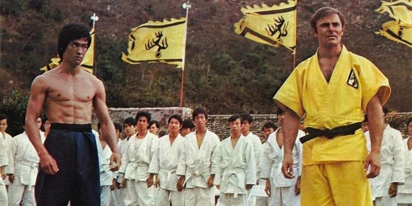 John Saxon and Bruce Lee stand in front of a crowd in Enter the Dragon