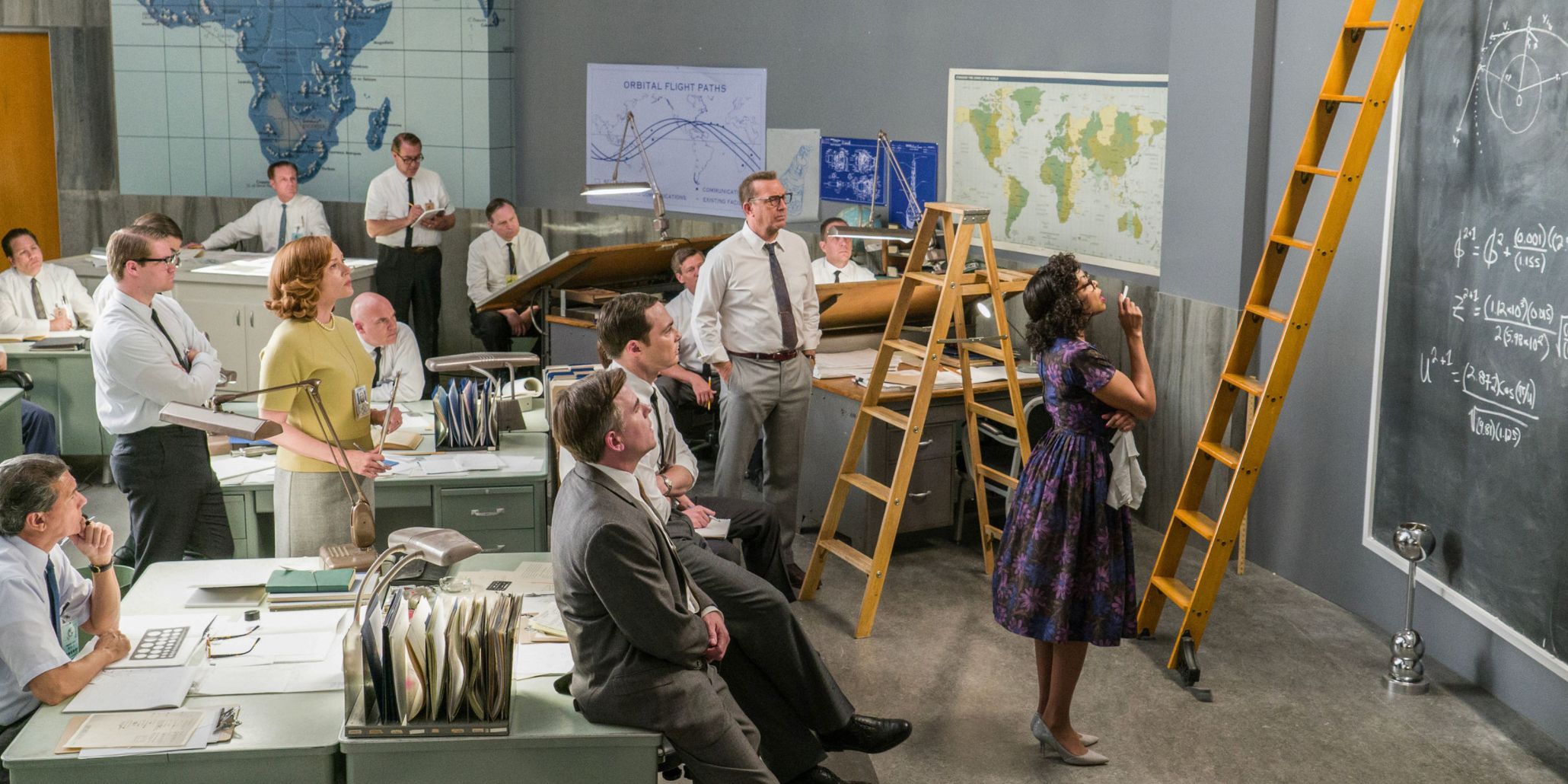 Katherine stands at the blackboard while the rest of the office watches her work in Hidden Figures