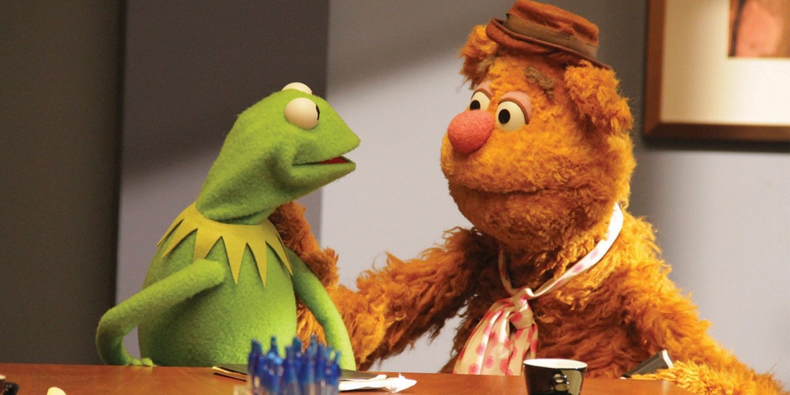 Kermit the Frog and Fozzie Bear sit together in The Muppets