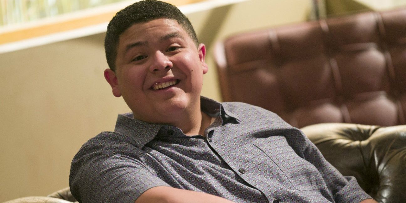 Manny Delgado in Modern Family, smiling while sitting on the couch