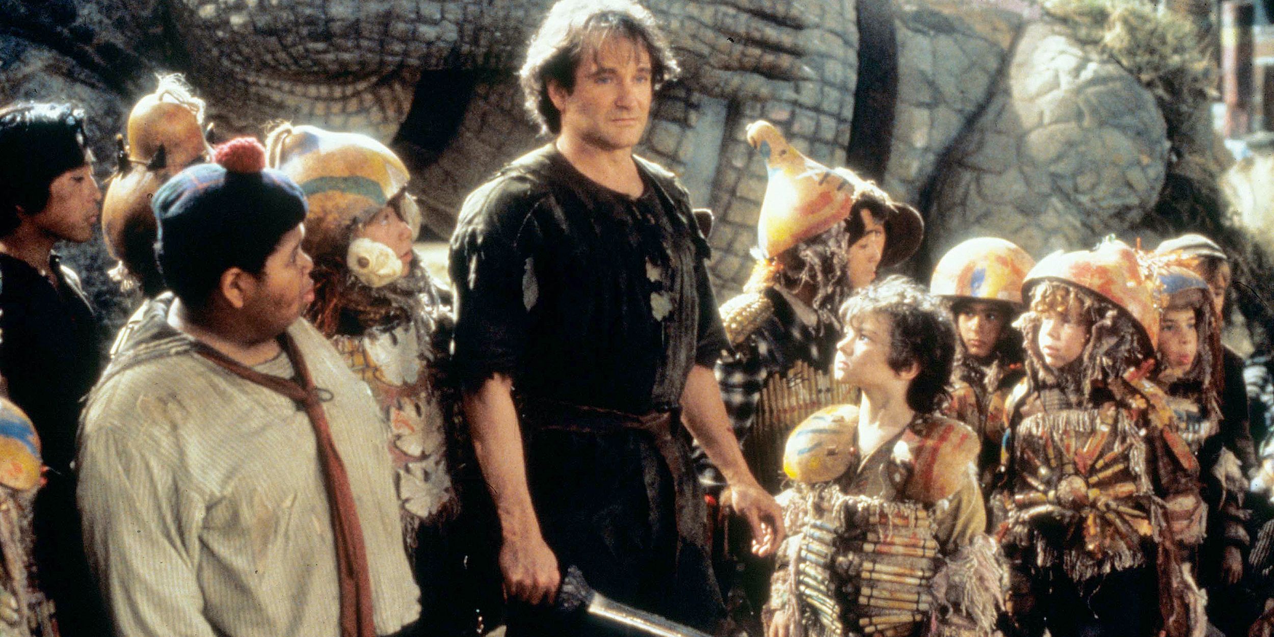 Peter holds his sword and stands with the Lost Boys in Hook