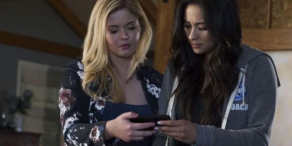Alsion and Emily looking at a phone on Pretty Little Liars