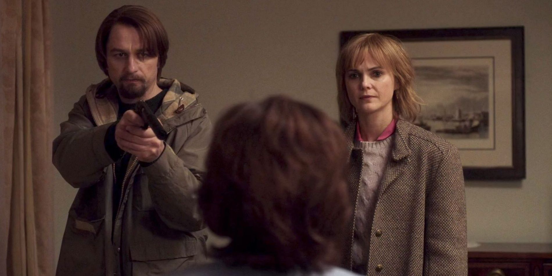 Philip points a gun while Elizabeth stares at the target in The Americans