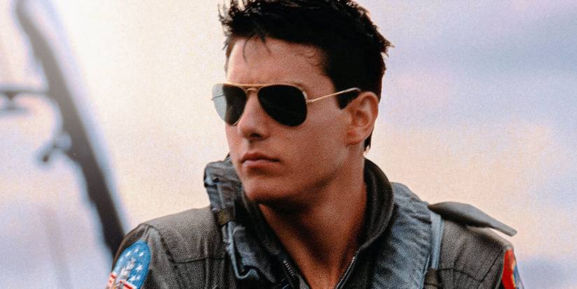 Tom Cruise as Maverick wearing sunglasses and looking into the distance in Top Gun