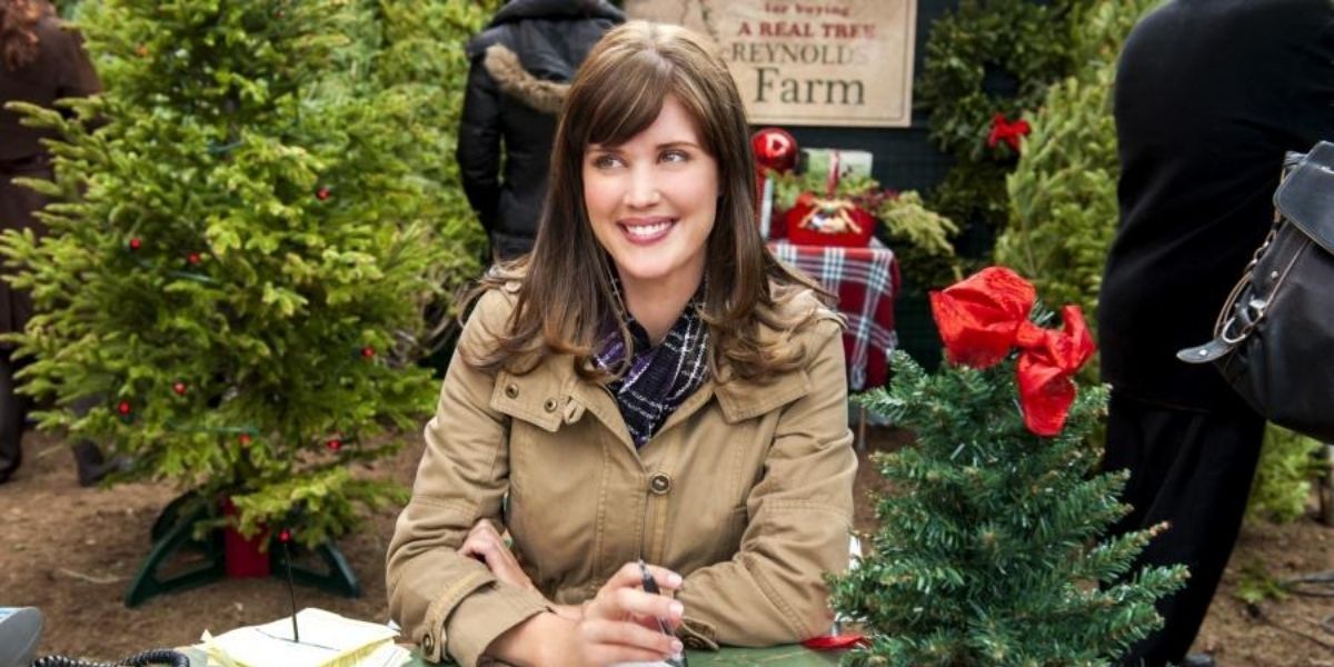 A woman selling Christmas trees at a market in a Hallmark Christmas movie