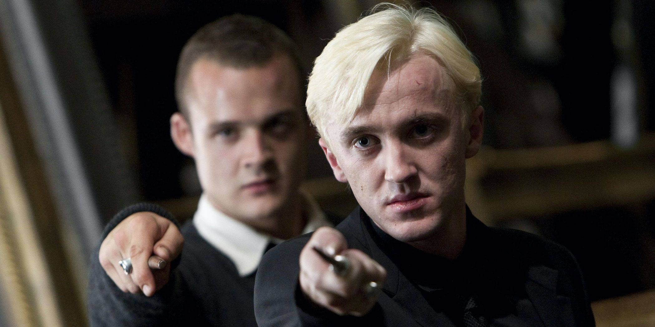 Malfoy points his wand with Goyle doing the same behind him