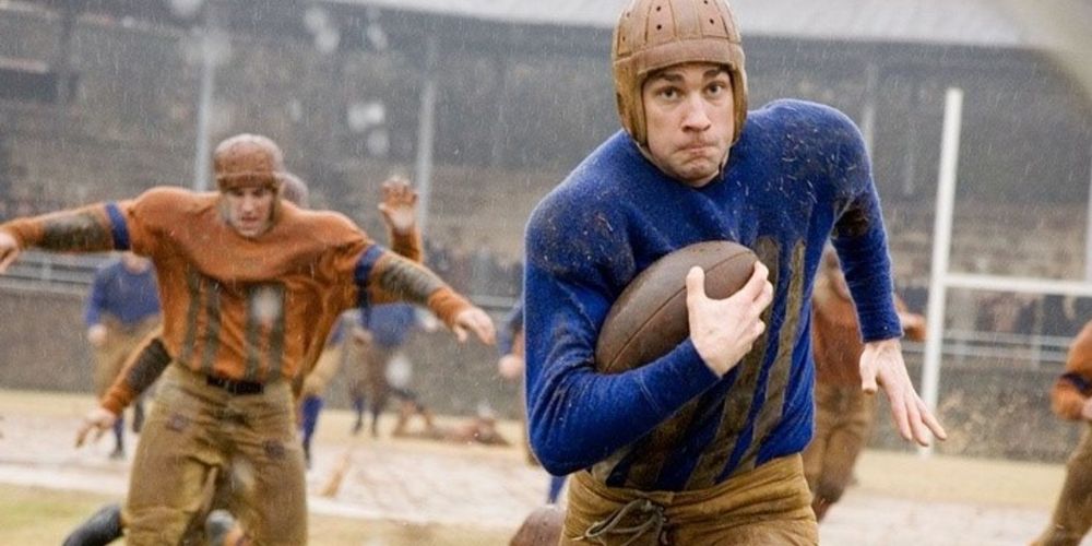 John Krasinski running with a football in his hands in a still from Leatherheads