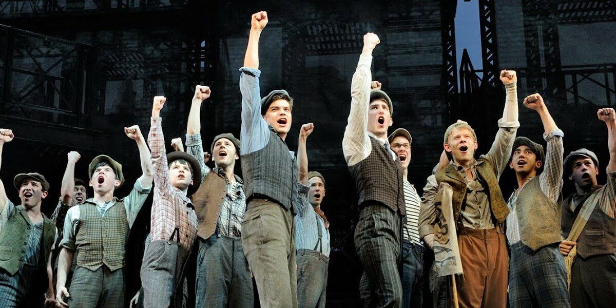 The cast of Disney's Newsies lifts their fists