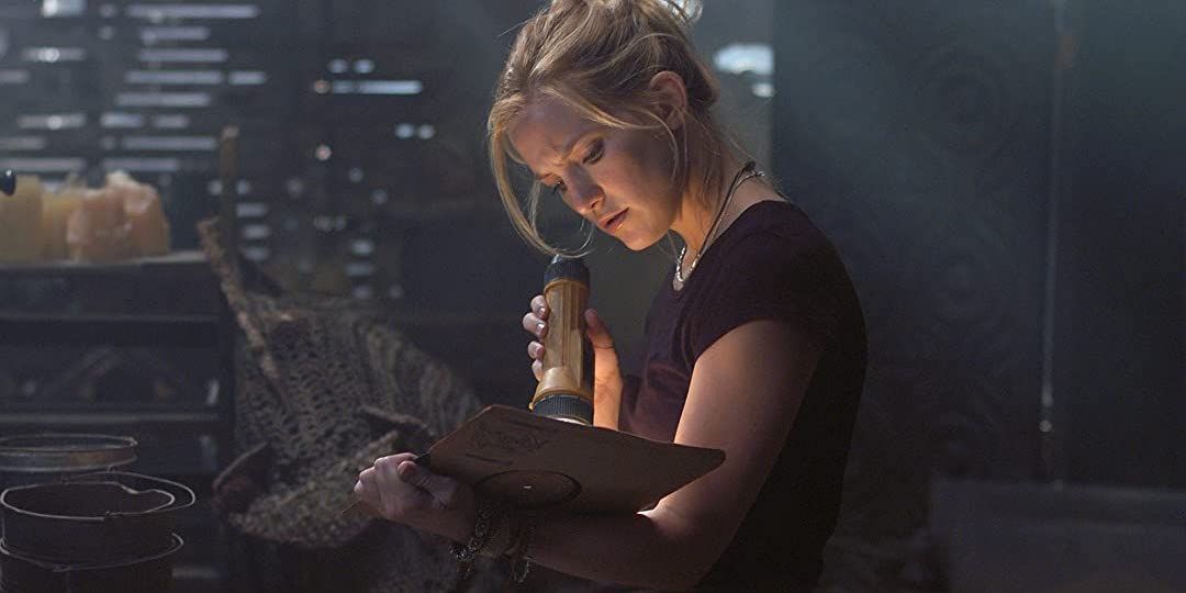 Kate Hudson reading a book with a flashlight in the hidden room in The Skeleton Key