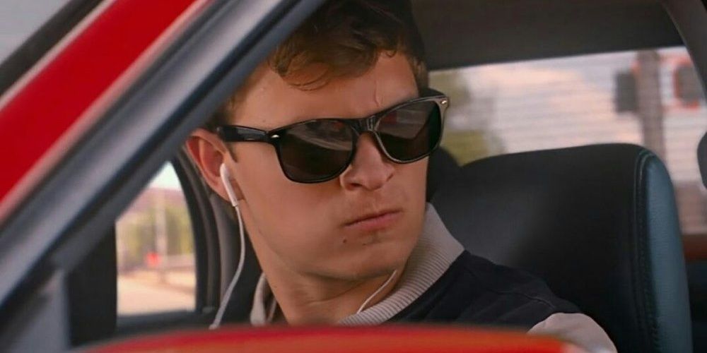 Baby listens to music with earphones behind the wheel in Baby Driver