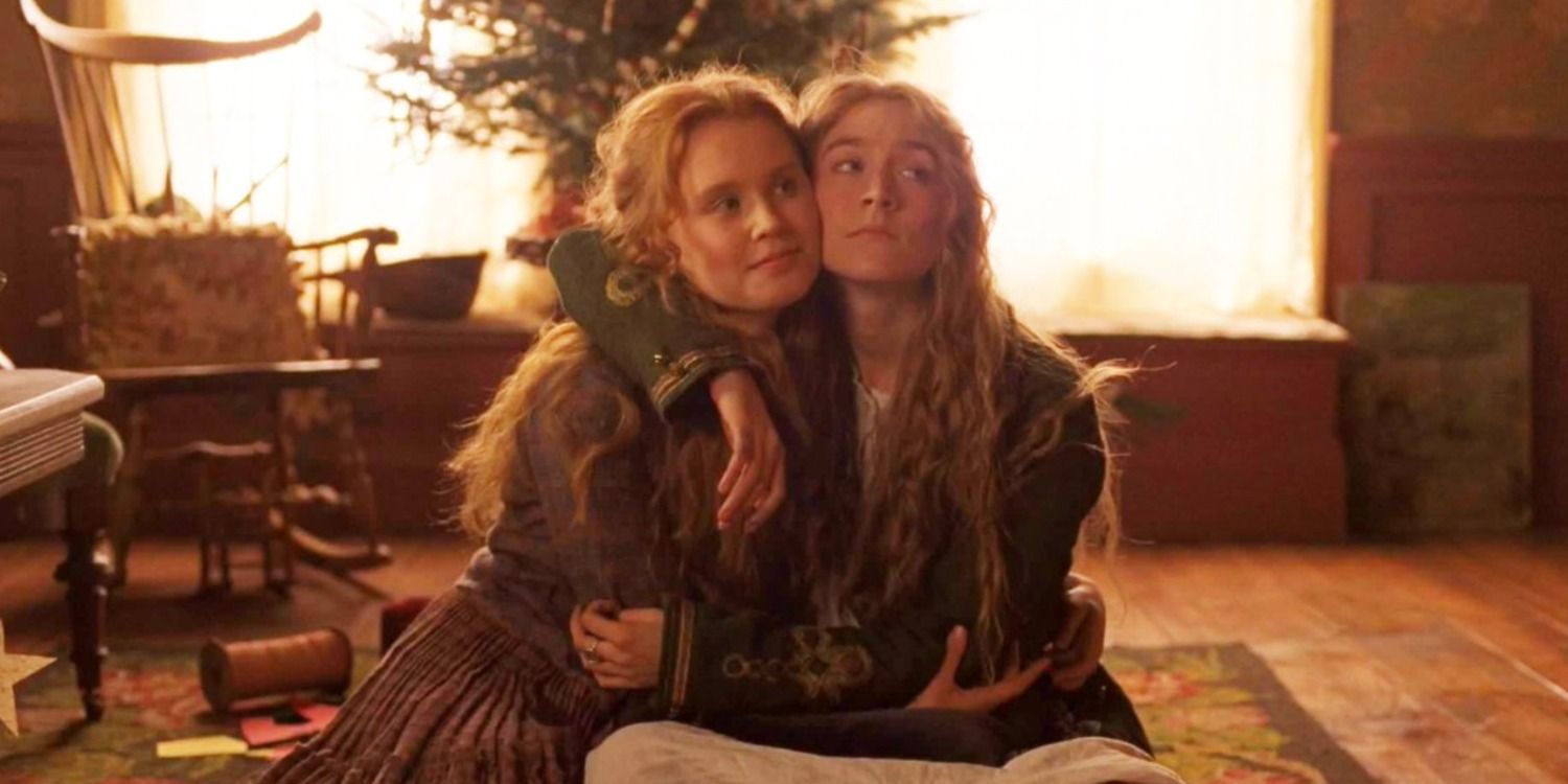 Beth and Jo sit on the floor in front of the Christmas tree with their arms around each other in Little Women