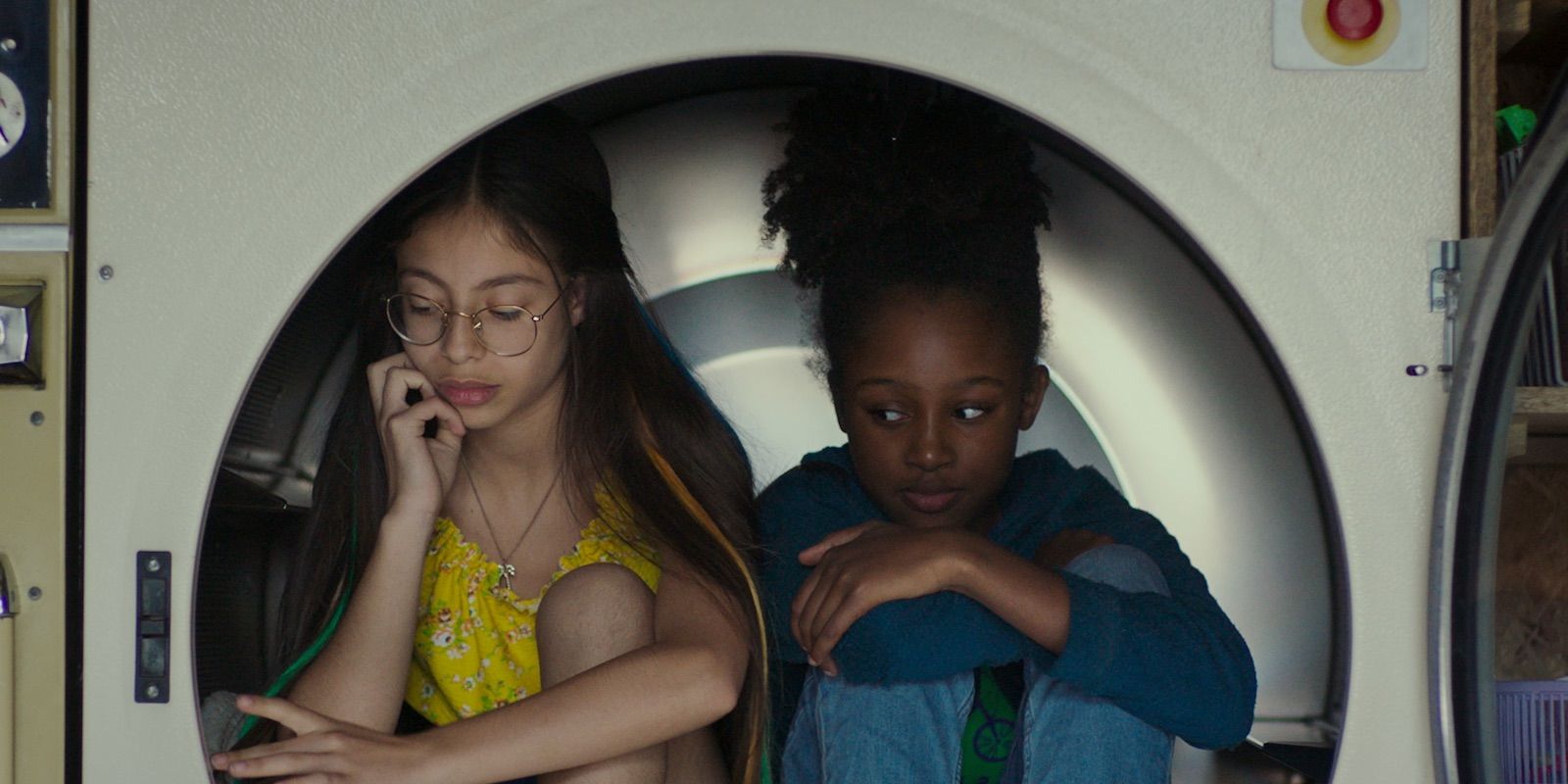 two girls sitting inside what looks like a dryer in Cuties