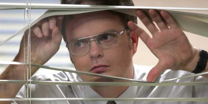Dwight peeks through the window with a deadpan expression.
