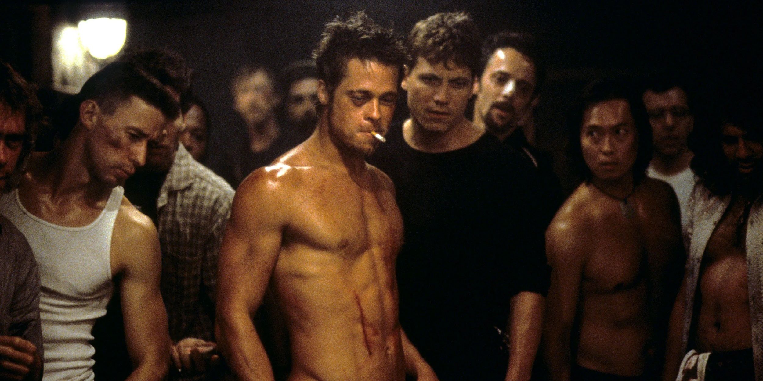 Brad Pitt shirtless surrounded by other fighters in Fight Club.