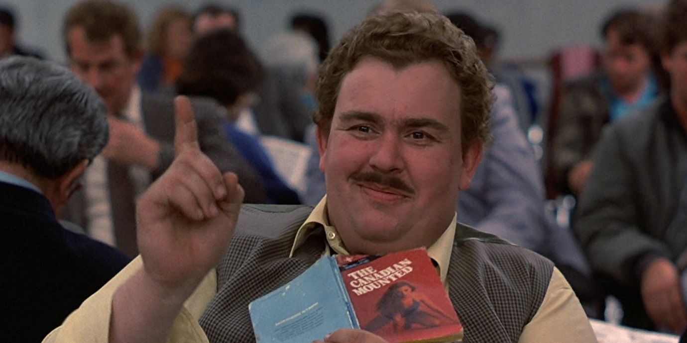 Del holding a book in Planes, Trains and Automobiles