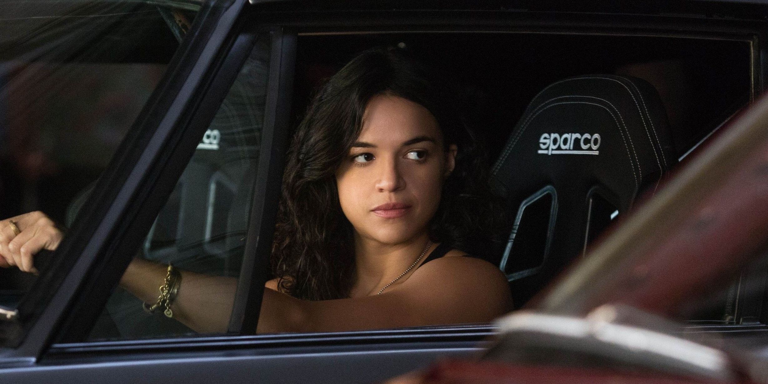 Letty Ortiz driving a car and looking out her window at someone