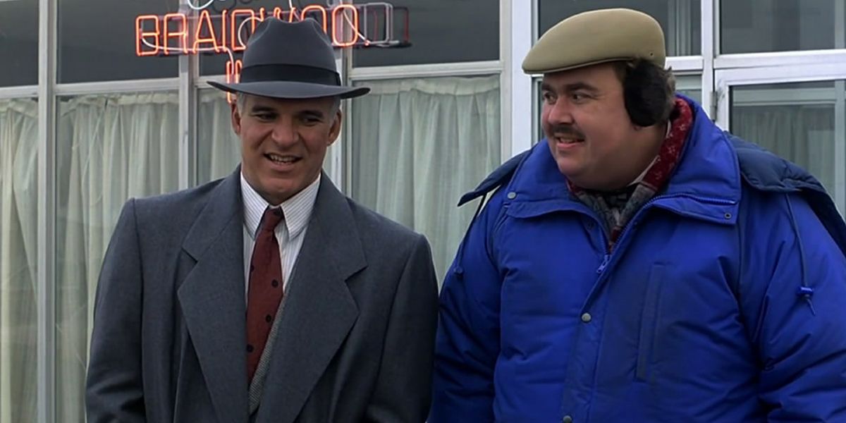 Neal and Del standing in a parking lot in Planes, Trains and Automobiles