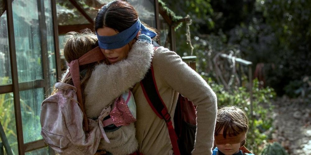 Sandra Bullock carrying a girl with a blindfold on her eyes in Bird Box