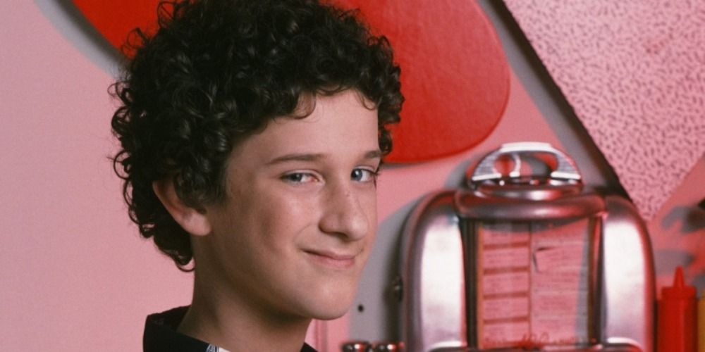 Screech smiles in front of a booth at the Max in Saved By The Bell