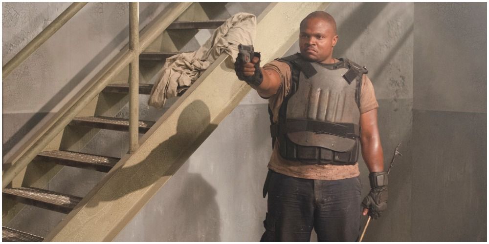 T-Dog from The Walking Dead, wearing a vest and pointing a gun.