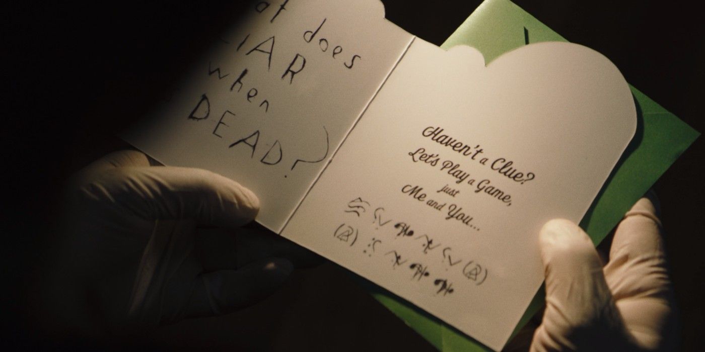 The Batman opens a card from the Riddler