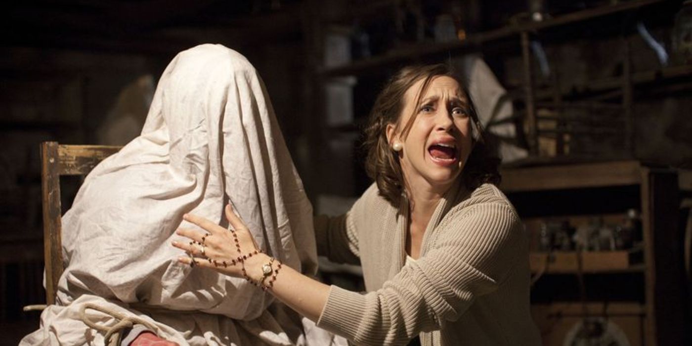 Vera Farmiga screaming with a demon under a sheet on a chair in The Conjuring