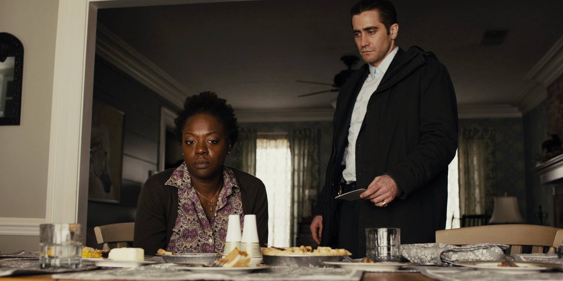 Jake Gyllenhaal standing next to Viola David at a table in Prisoners