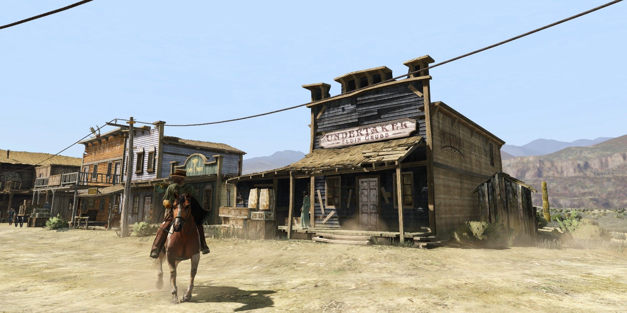 John riding a horse in front of Armadillo's undertaker building in RDR2.
