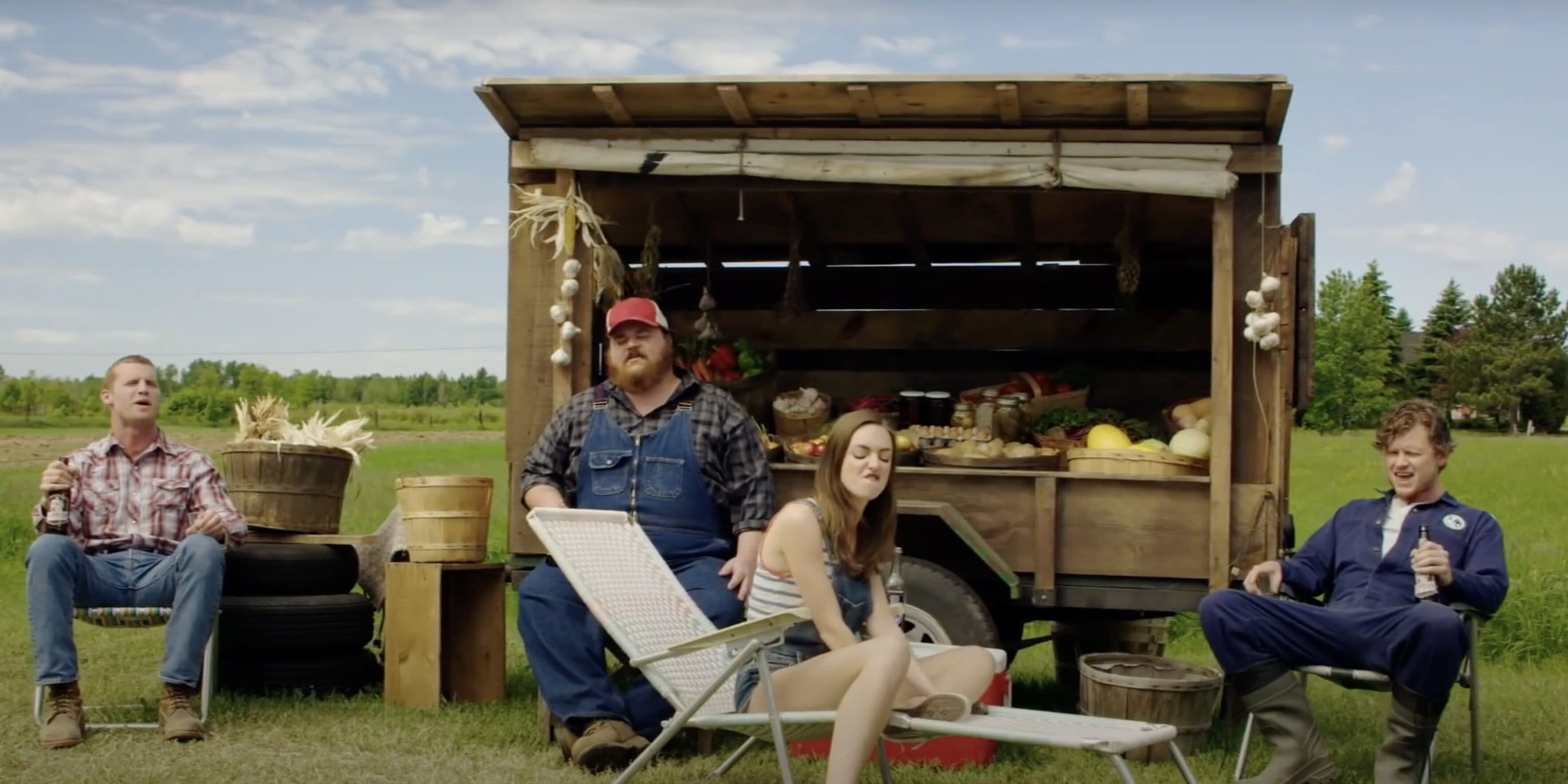 The Cast of Letterkenny sitting an drinking outside a food stand 