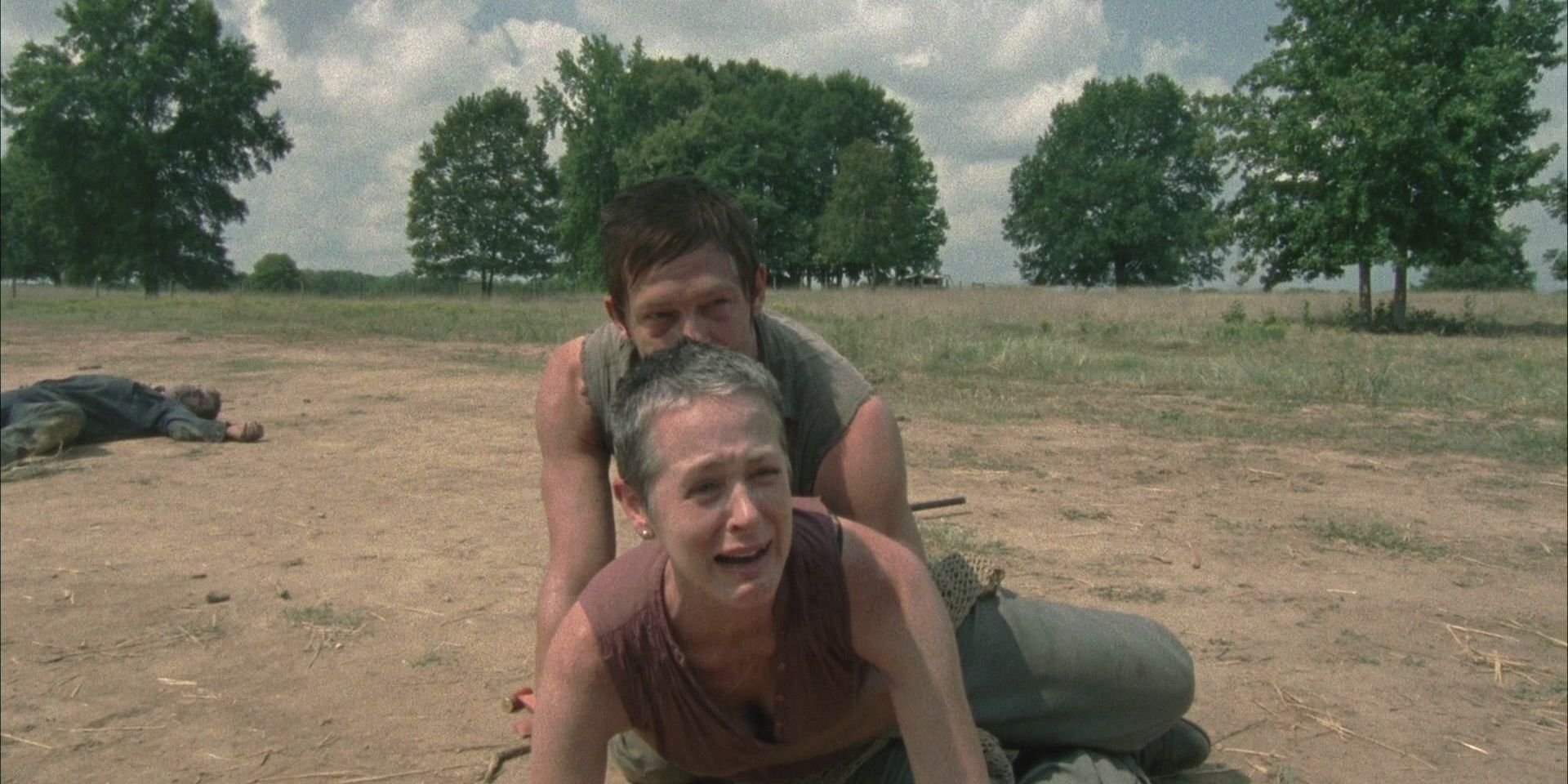 Carol grieving and Daryl restraining her.