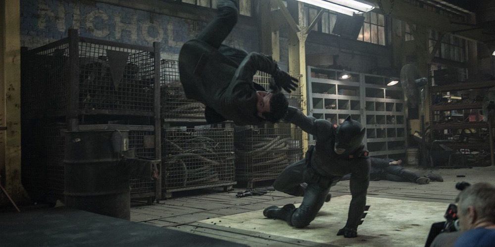 Batman fighting henchmen in the warehouse