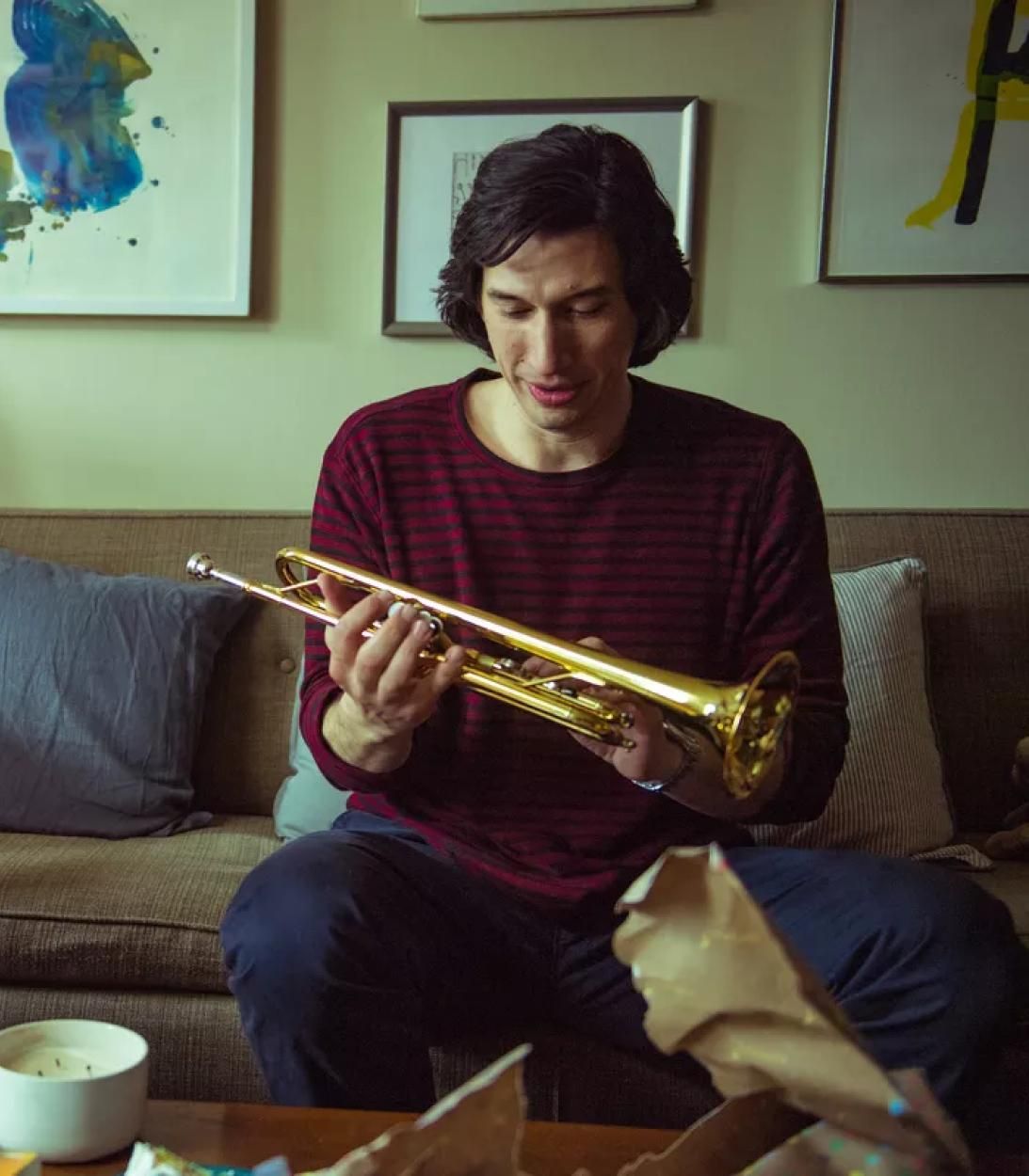 Adam Driver holding a trumpet in Marriage Story