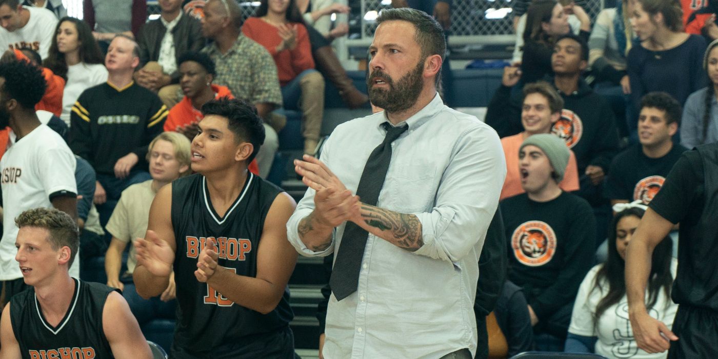 Jack (Ben Affleck) bertepuk tangan sambil berdiri di depan penonton pada pertandingan bola basket di The Way Back (2020).
