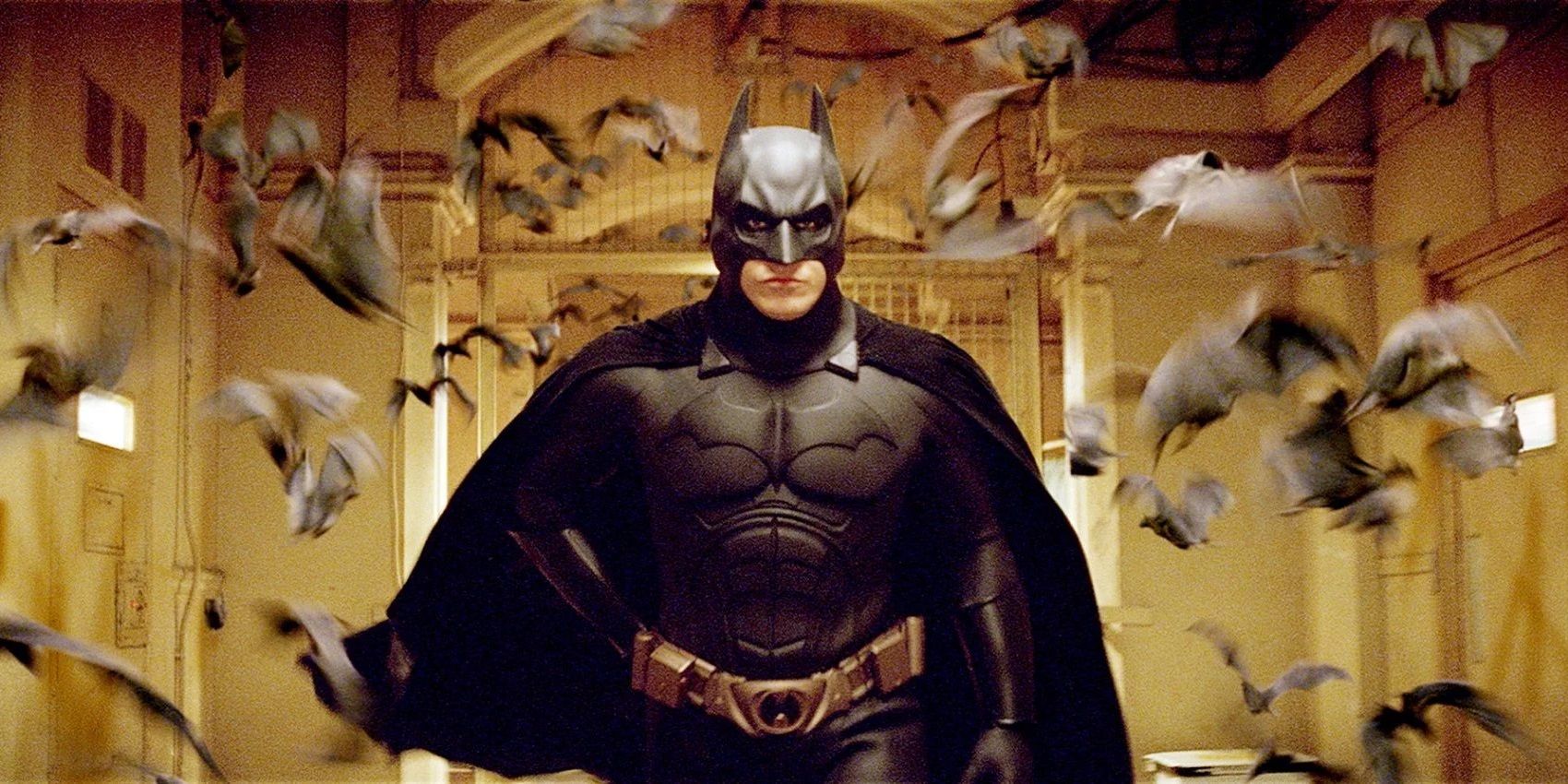 Batman running down a hall with bats flying behind him in Batman Begins.
