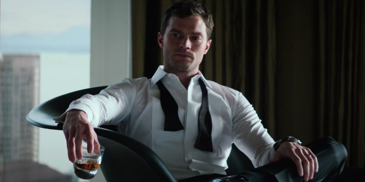 Christian Grey sitting down holding a glass in Fifty Shades Freed