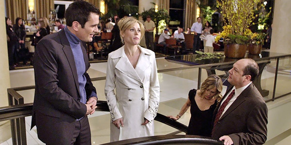Claire stuck in an escalator, Phil beside her and a couple behind them in a hotel lobby in Modern Family
