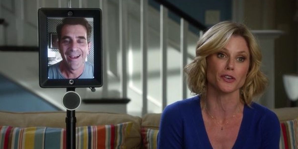 Phil en una pantalla y Claire sentada a su lado en Modern Family