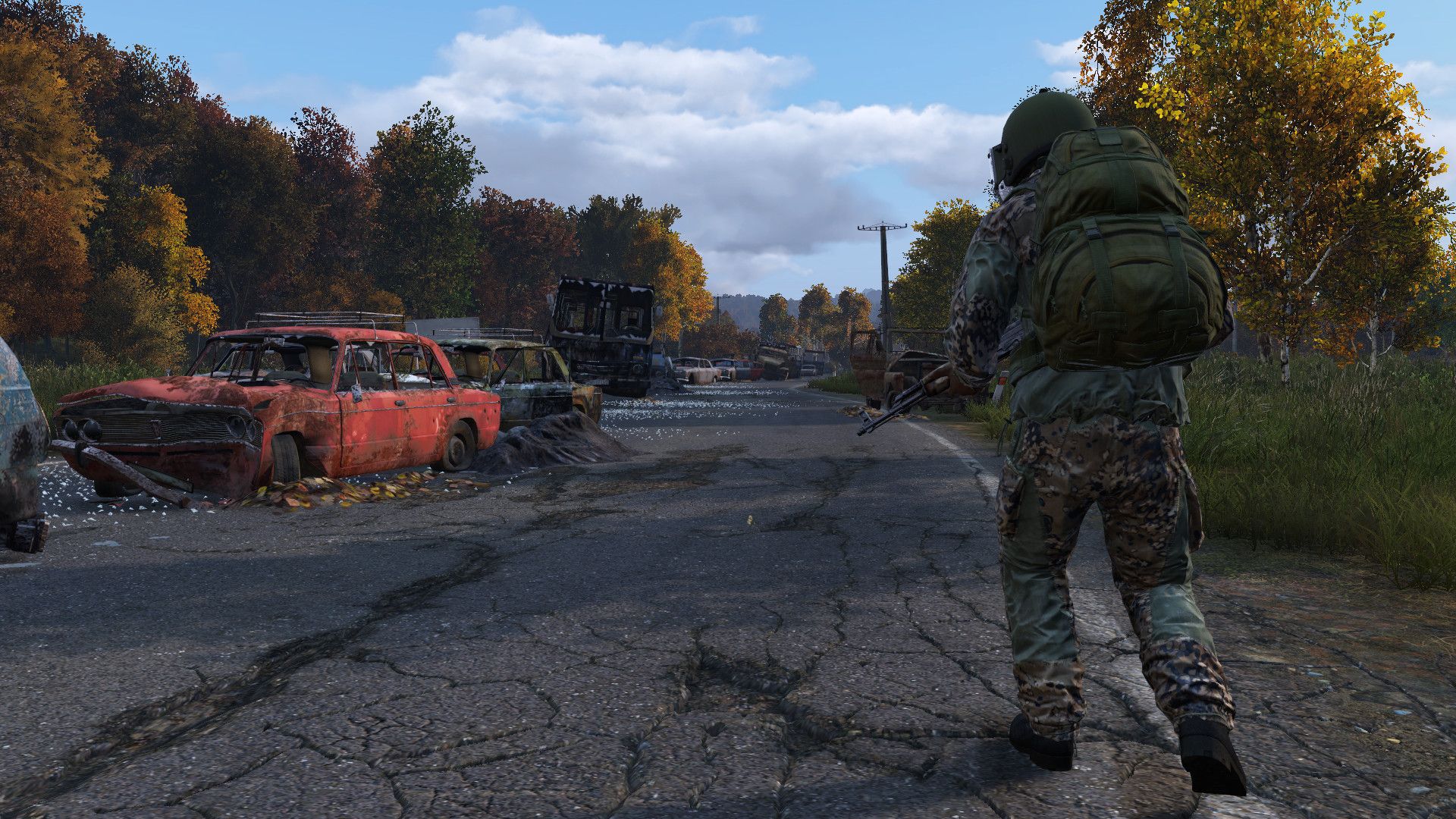 A DayZ player walks down a road filled with abandoned vehicles