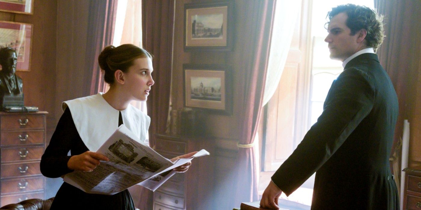 Enola Holmes holding a newspaper and looking at Sherlock Holmes in Enola Holmes