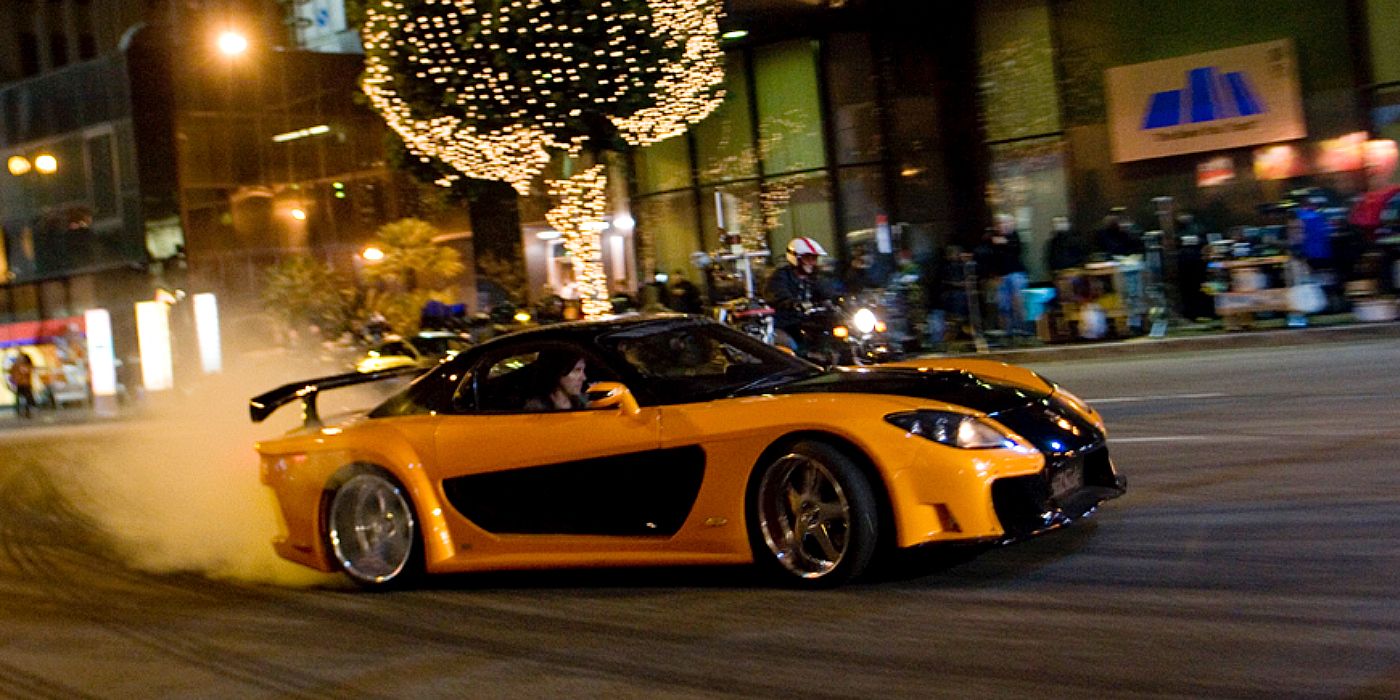 Han drifts through Tokyo in an orange and black Mazda RX7 in Tokyo Drift