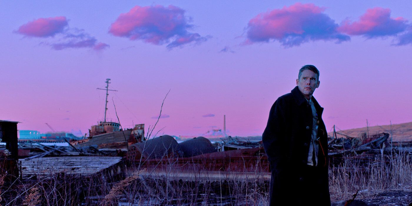 Ethan Hawke walks past a toxic waste site and a purplish sky in First Reformed